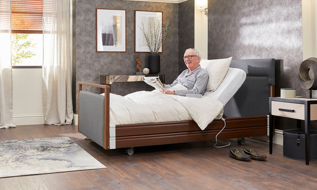 A older man sat upright in a profiling bed holding a newspaper