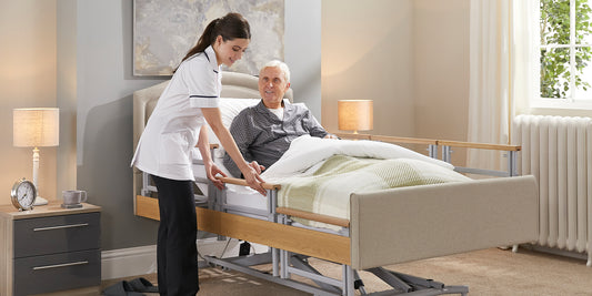A female carer with brown hair pulling up a side rail on a profiling care bed 