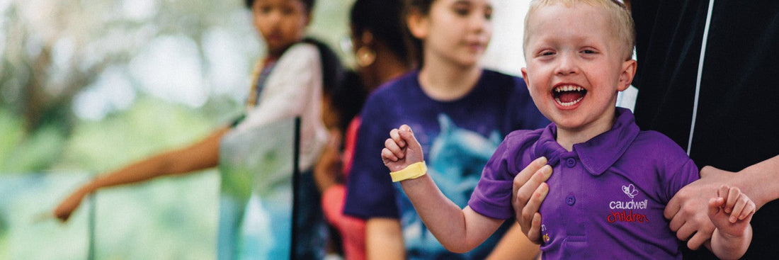 A young child smiling wearing a purple polo shirt
