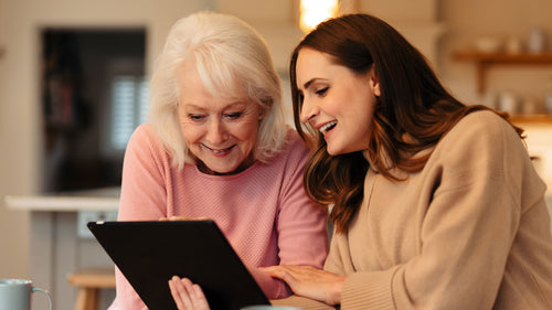 Mother and Daughter looking at a tablet together at the table.