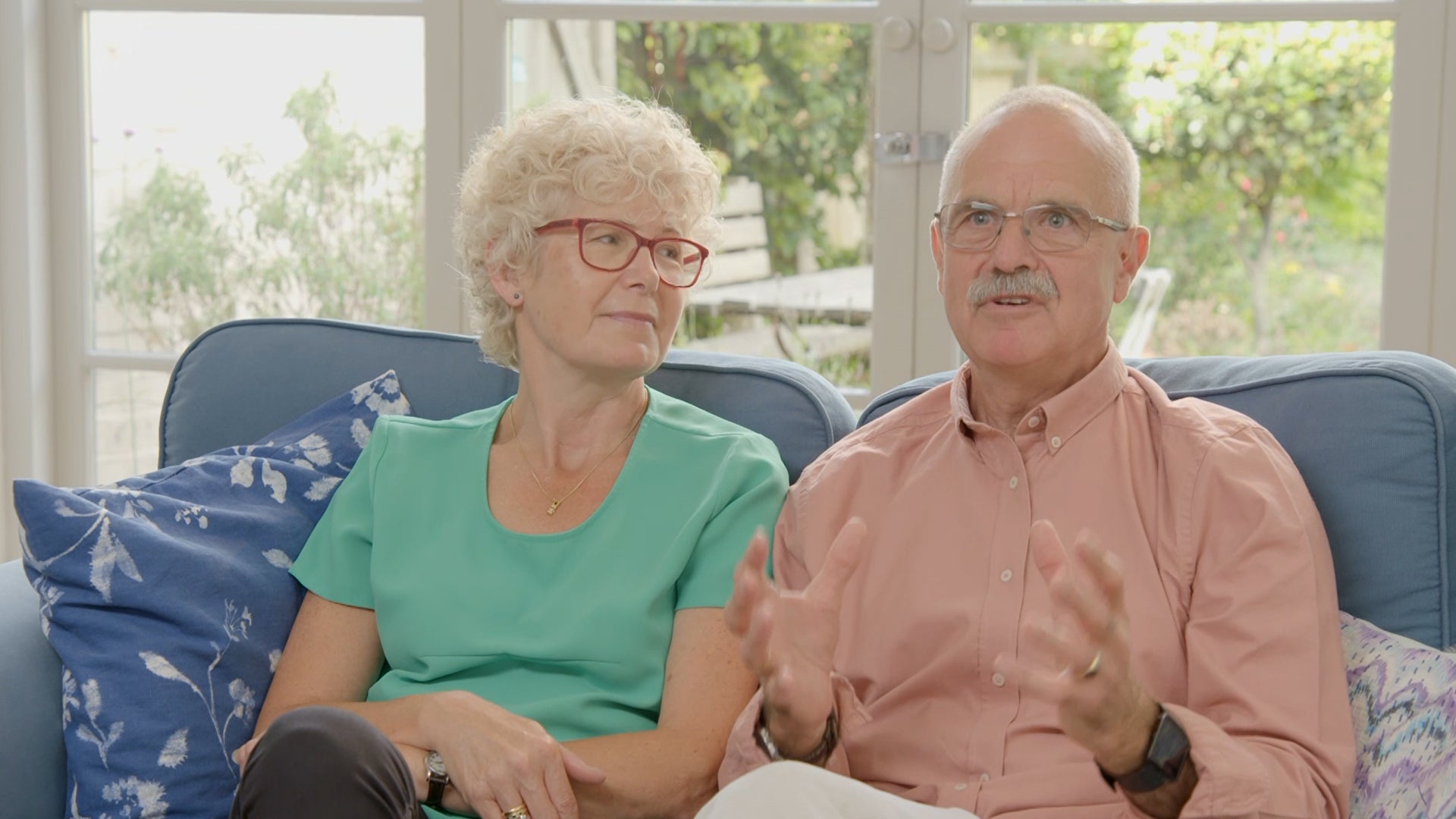 Opera customer's David & Carolynn sat on a sofa giving a testimonial.