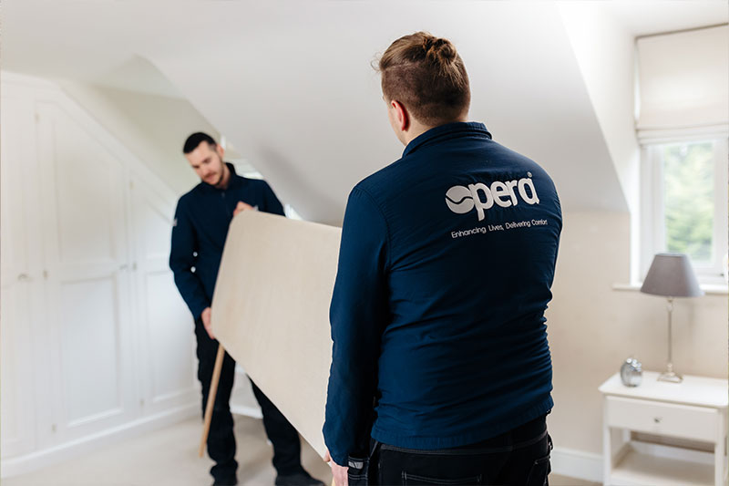 Two men in Opera Beds uniform, removing a headboard from a bedroom.