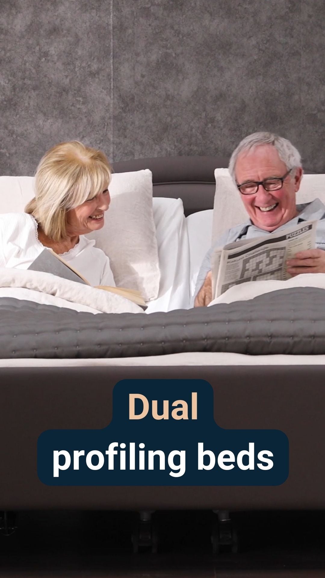 A couple sat smiling in a dual profiling bed with the caption 'Dual profiling beds'