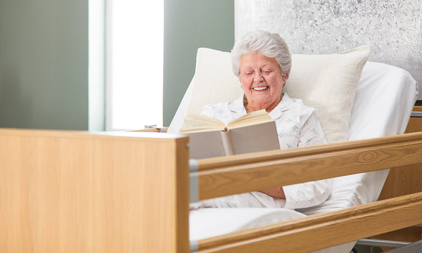 Older woman reading in an Opera Classic profiling bed.
