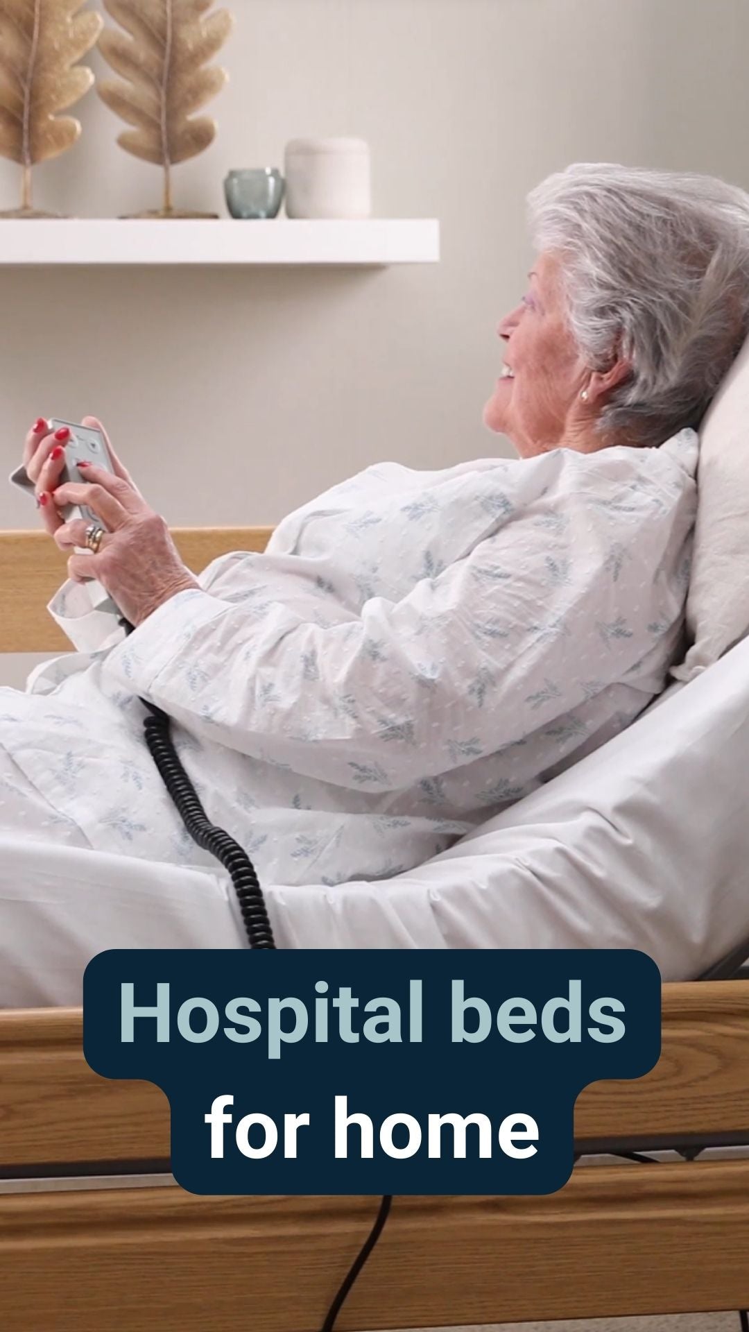 A lady sat smiling holding a remote in a profiling bed with the caption 'Hospital beds for home'