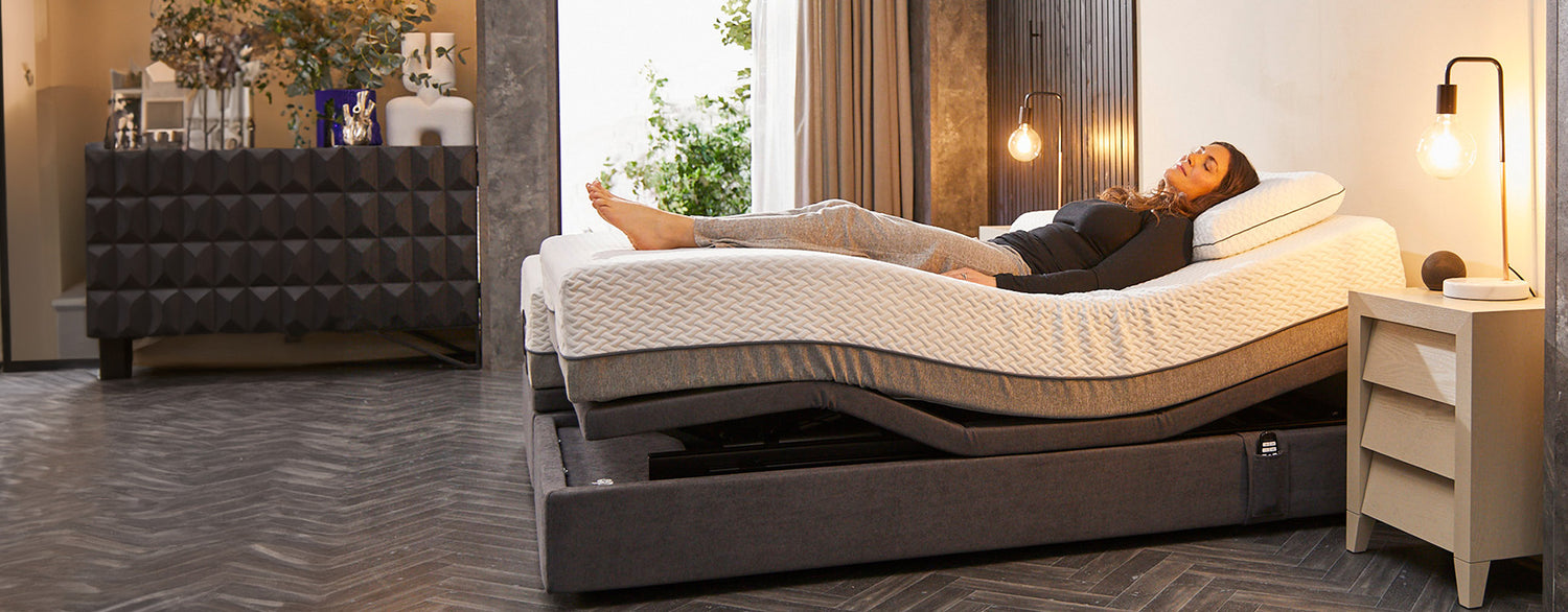 A lady laid in a comfortable position on an adjustable bed with her legs elevated and back adjusted