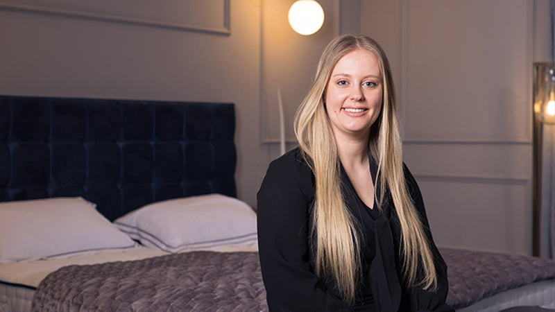 Opera employee sat on the edge of an adjustable bed smiling