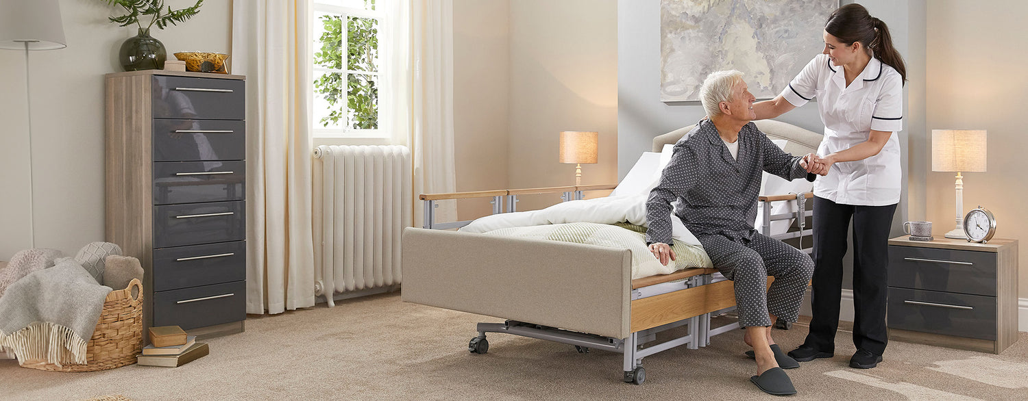 A carer helping an older man get out of a profiling bed with side rails