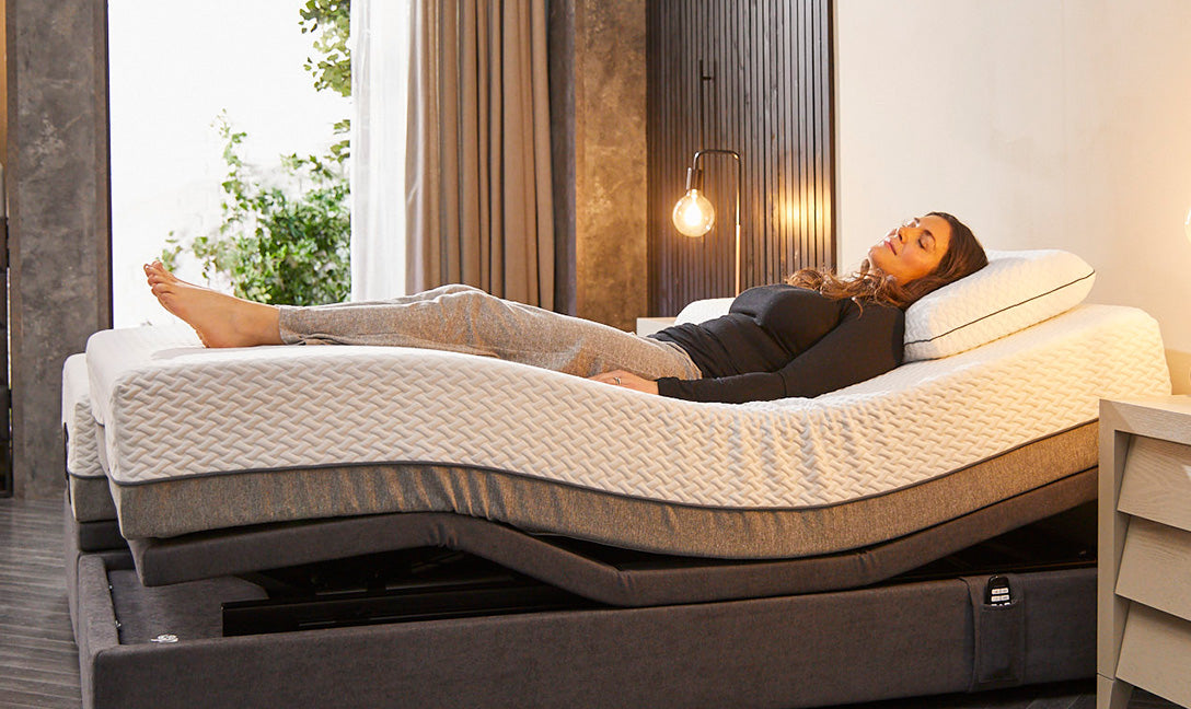 A lady laid in a comfortable position on an adjustable bed with her legs elevated and back adjusted