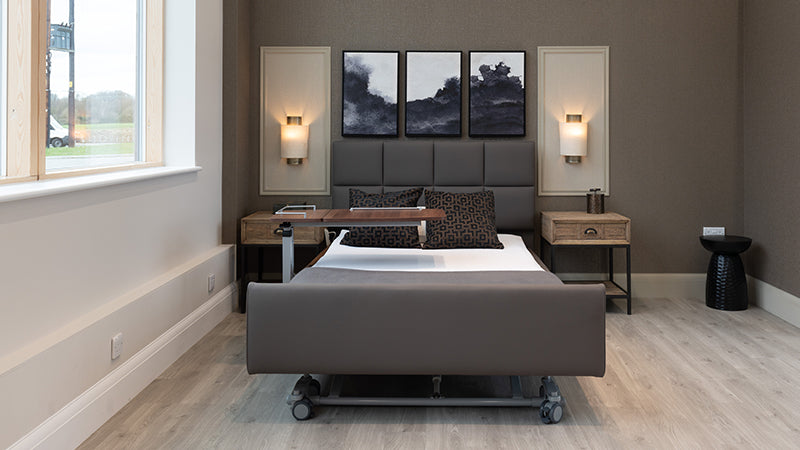 Opera Profiling bed in brown leather in a modern bedroom setting with an overbed table