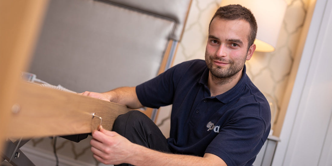 A gentleman holding an allen key smiling to the camera wearing a dark blue polo with the Opera logo