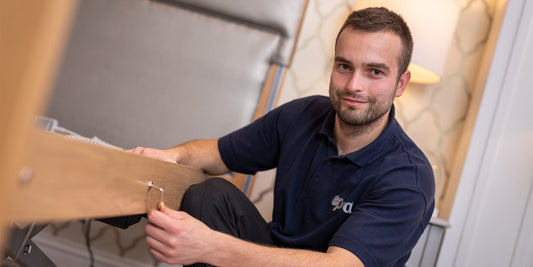 A gentleman holding an allen key smiling to the camera wearing a dark blue polo with the Opera logo