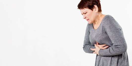 A woman wearing a grey jumper holding her lower chest