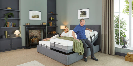 An elderly couple in bed with the gentleman holding a grab rail and the bed is raised up to make it easier to exit