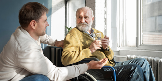 A older gentleman sat in a wheelchair next to his son