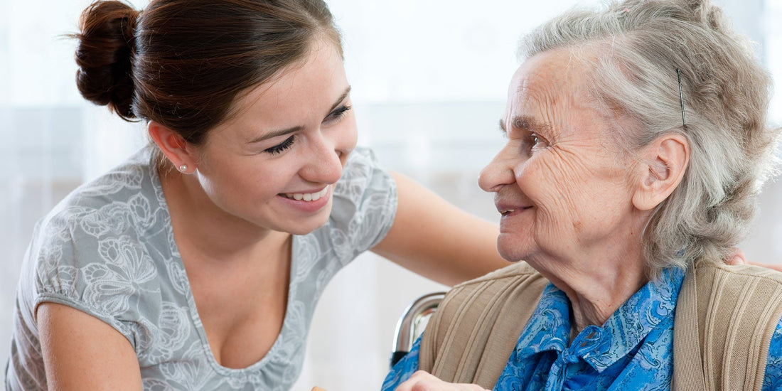 A woman with brown hair putting her arm around her elderly grandmother's 
