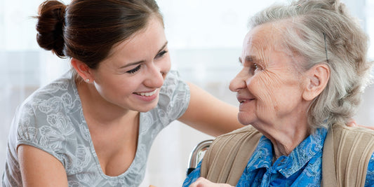 A woman with brown hair putting her arm around her elderly grandmother's 