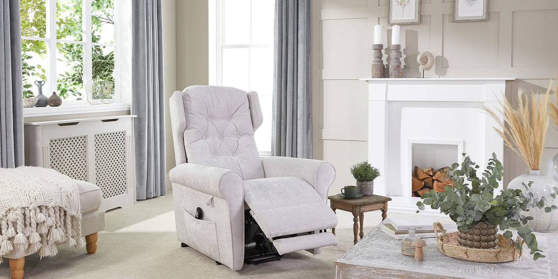 A light grey riser recliner chair in a living room with cream carpet