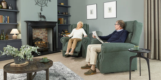 An elderly couple sat at home in a riser recliner chair 