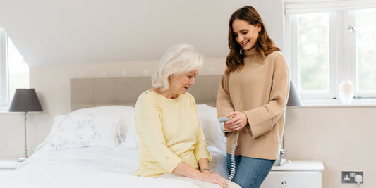 Mother and daughter in a bedroom at home, the daughter is holding a wired profiling bed hand control