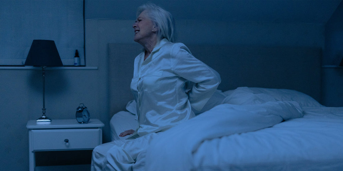 Older lady holding her lower back in pain in the middle of the night