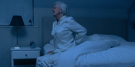 Older lady holding her lower back in pain in the middle of the night