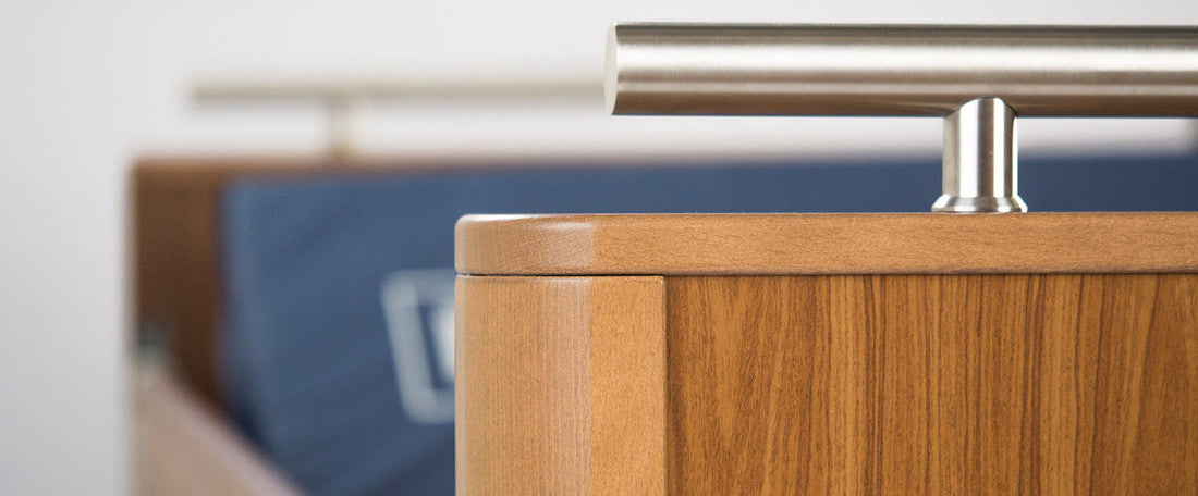 A close up of the foot end of a wooden profiling bed with a blue pressure care mattress