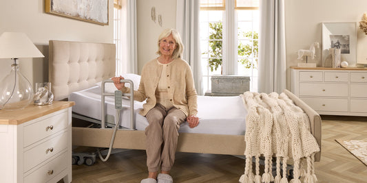 An older lady holding onto a grab rail on a profiling care bed
