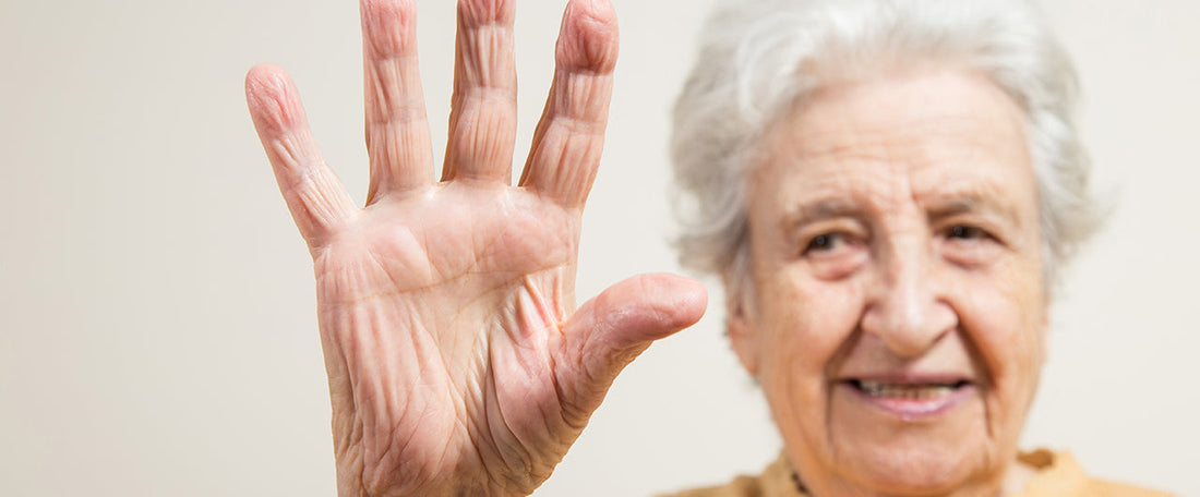 A elderly lady holding 5 fingers up