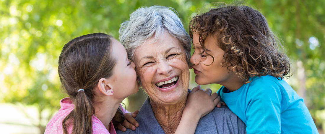 A elderly lady being kissed on her face by two children