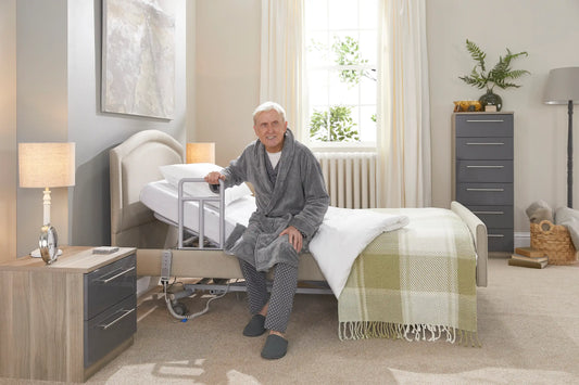 An older gentleman wearing gray pyjamas stretching at the end of his bed