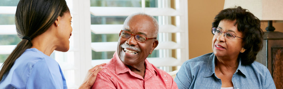 A older gentleman smiling talking to two female carers