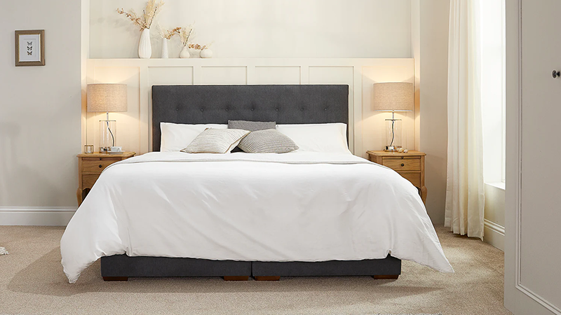 A front facing view of a dark grey Opera adjustable bed dressed with white bedding in a well lit room.