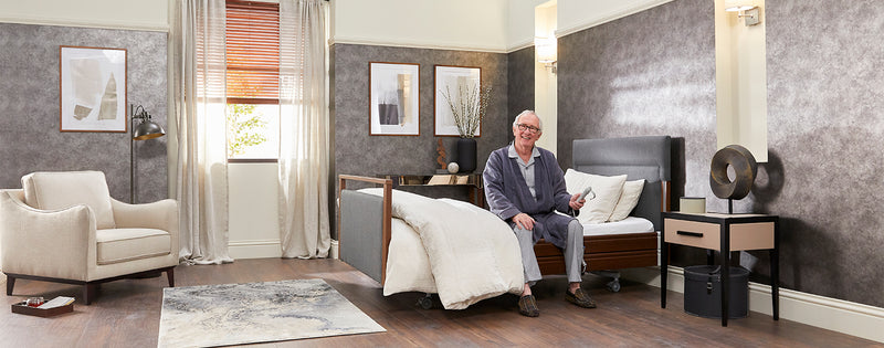 Older man with arthritis sat on a profiling bed