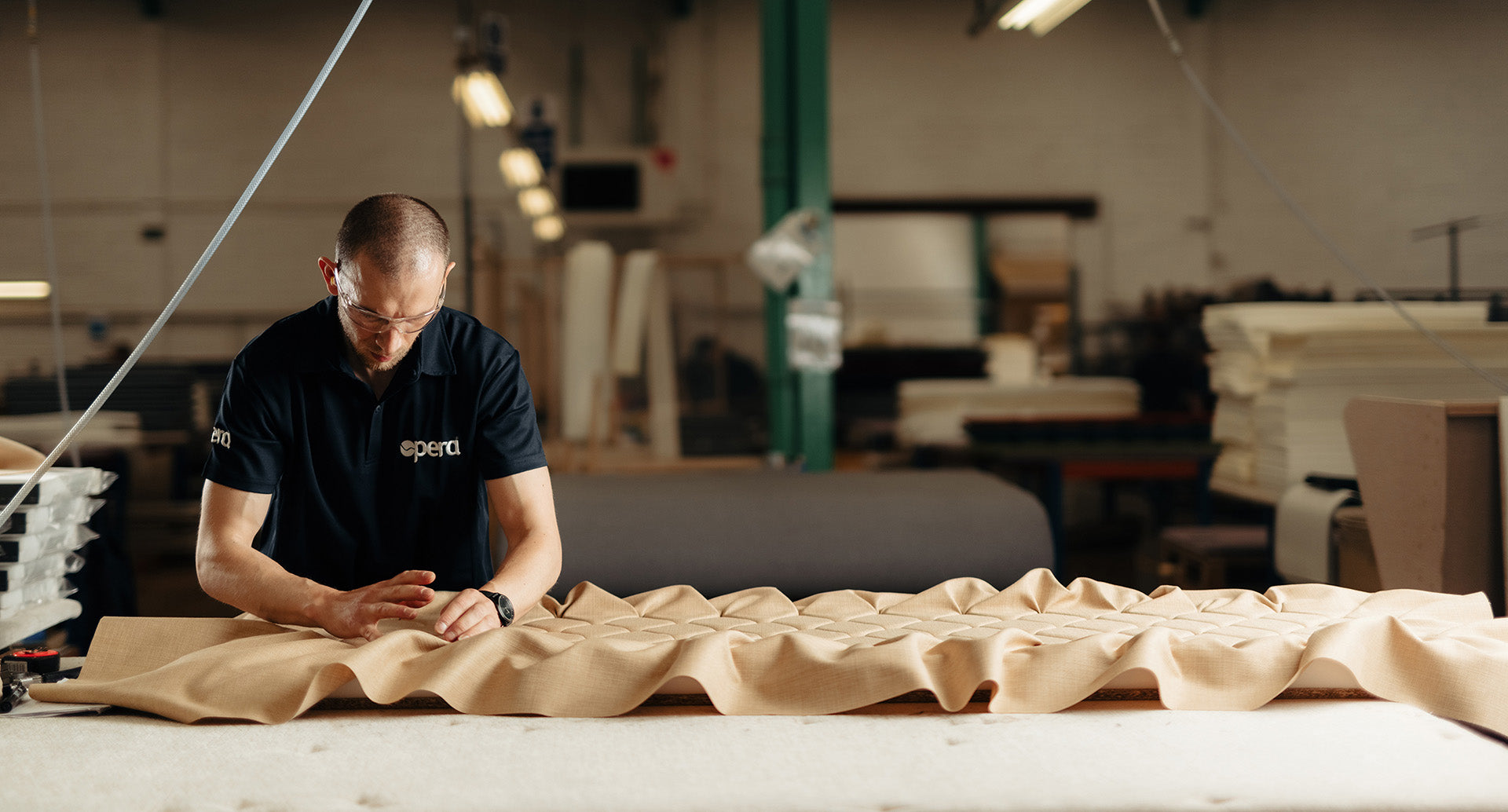 Opera manufacturer working with some bed upholstery material in a warehouse.