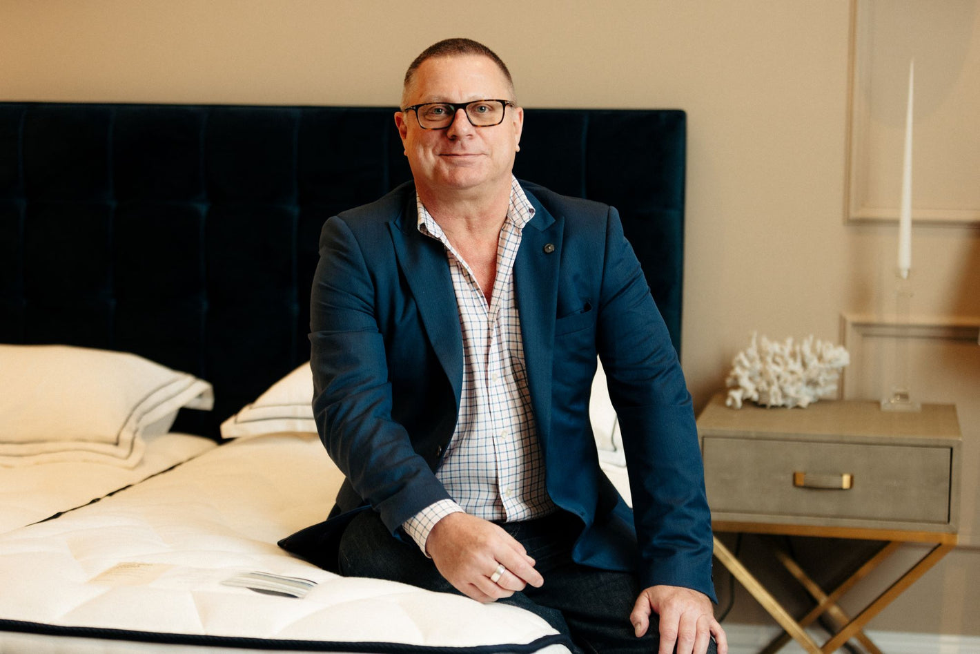 Dean, a man wearing glasses and a blue suit sitting on the end of an Opera Bed