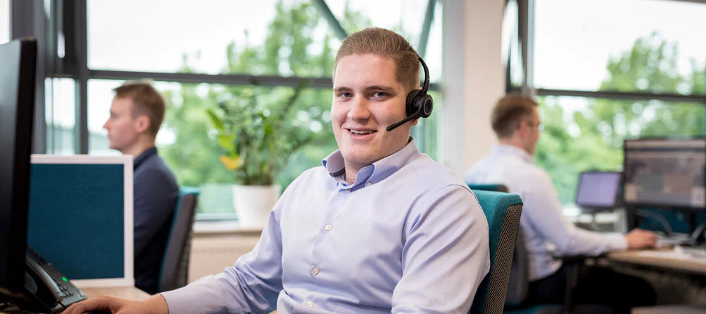 A smiling Opera advisor sat at a desk wearing a headset