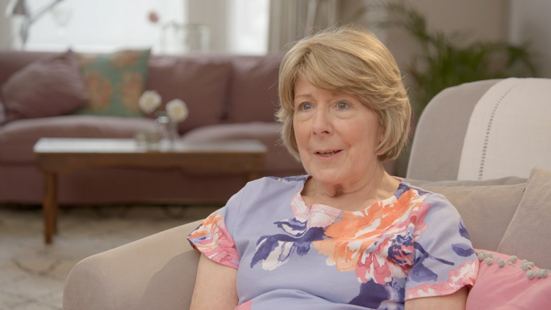 Opera Bed's customer Jane Phillips sat on a sofa giving a testimonial