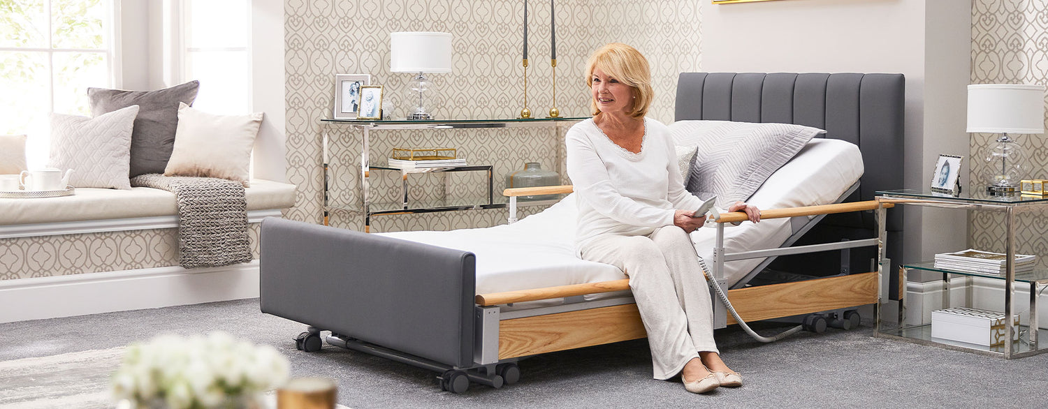 Older woman sitting on an Opera profiling bed, using the handset.