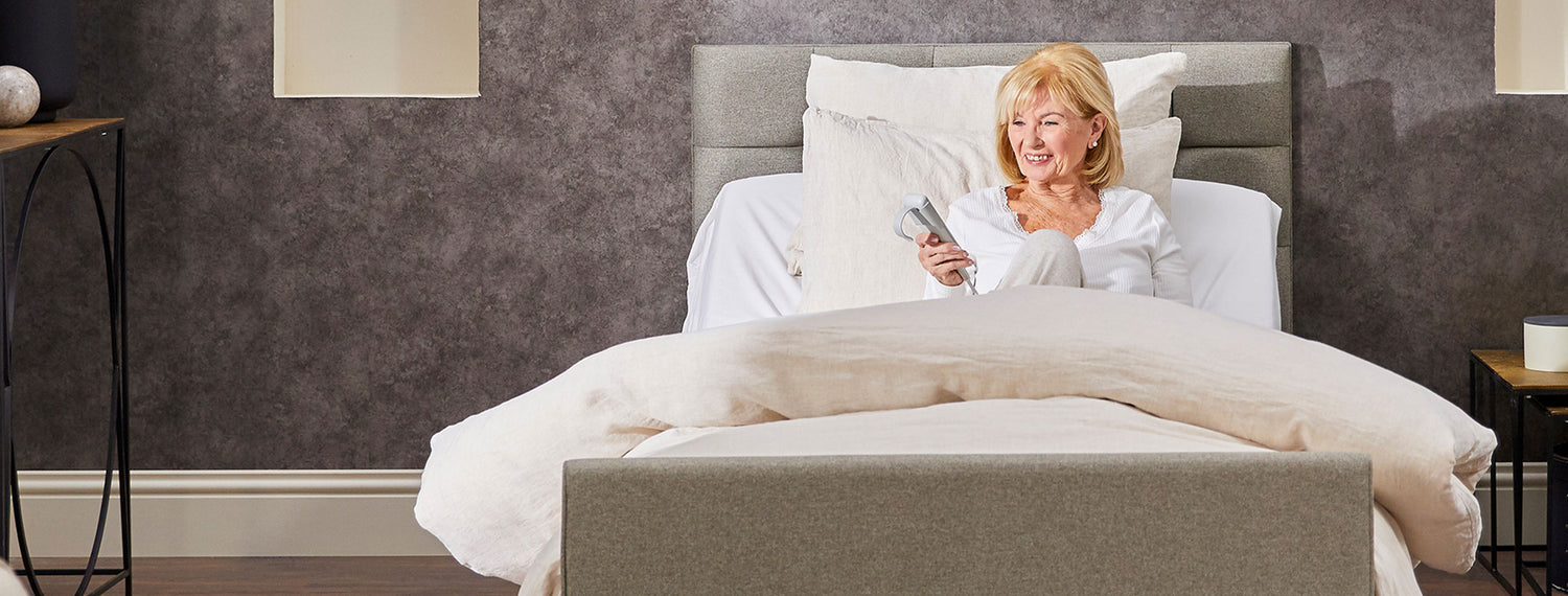 Older woman with blonde hair, using the remote in an Opera profiling bed.