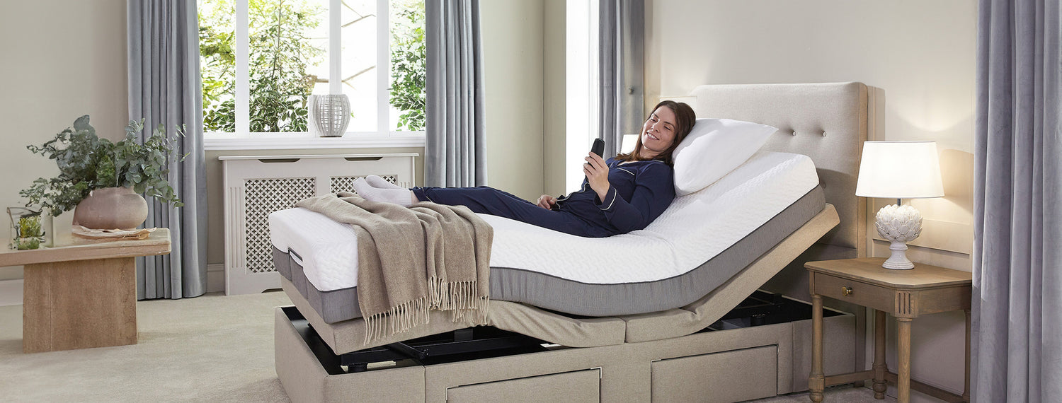 Woman in navy pyjamas lying in an adjustable bed holding the control 