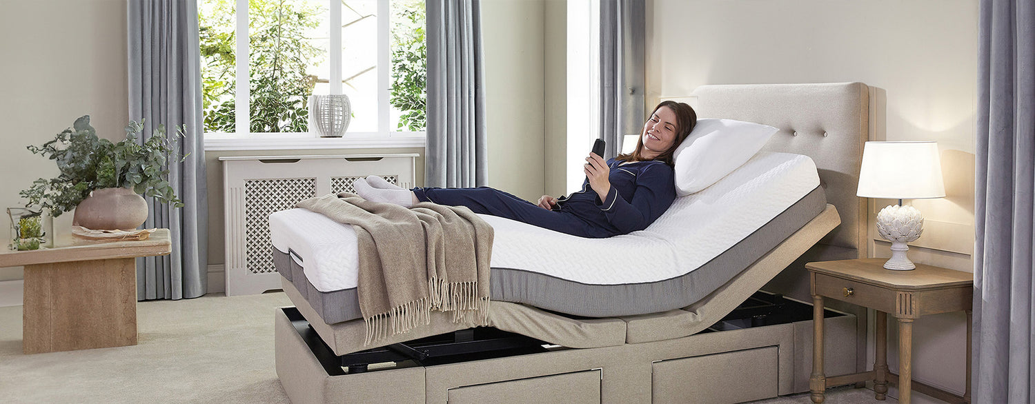 Woman in navy pyjamas lying in an adjustable bed holding the control 