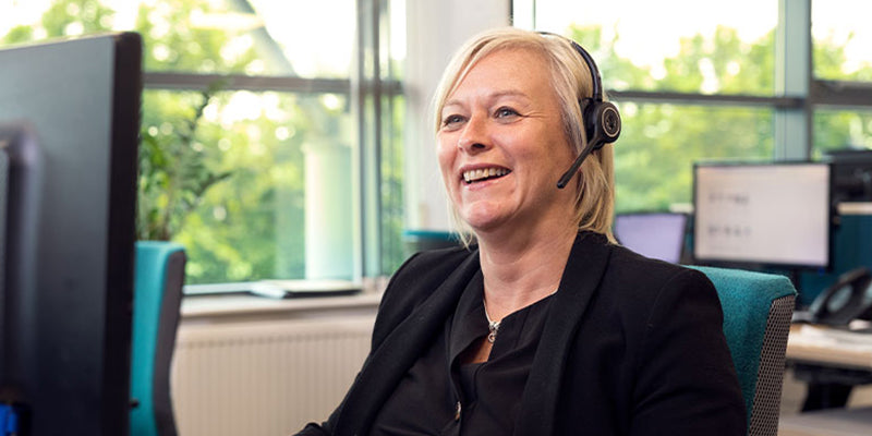 Opera employee with a headset on sat at her computer in an office