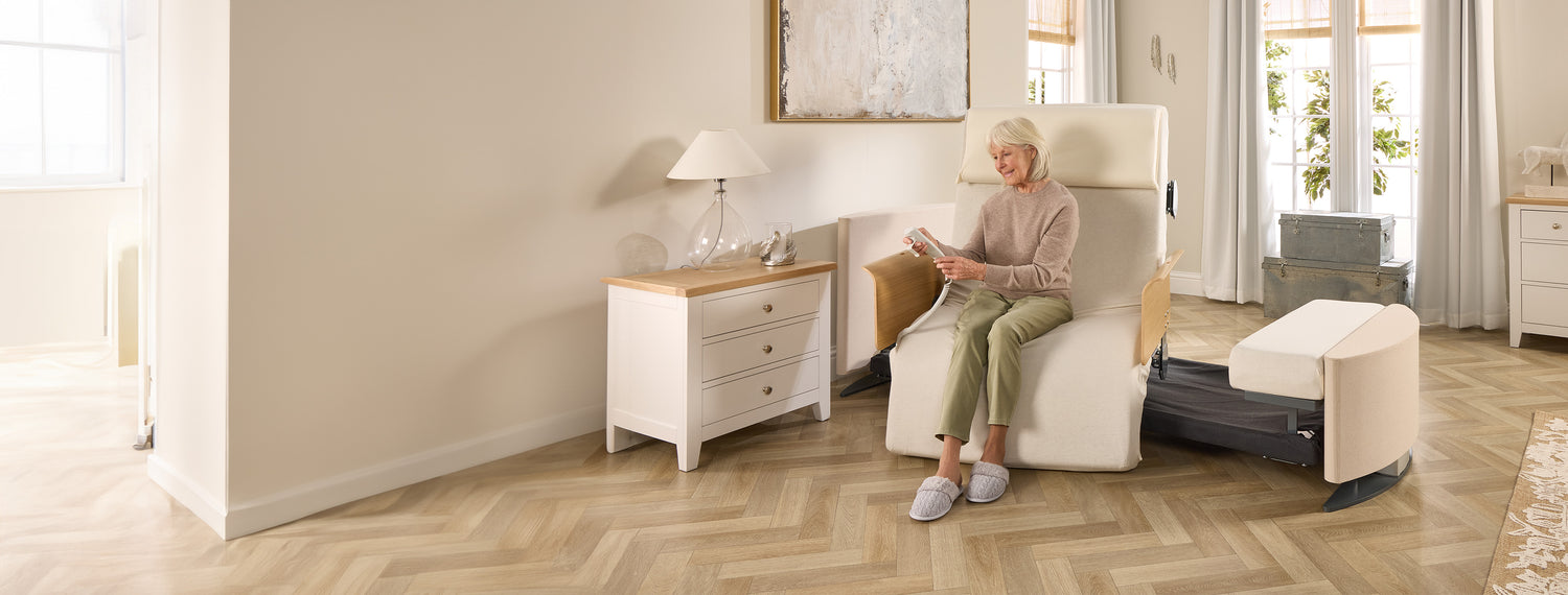 Lady sitting in a Rotating Chair Bed in the chair position, holding the remote control.