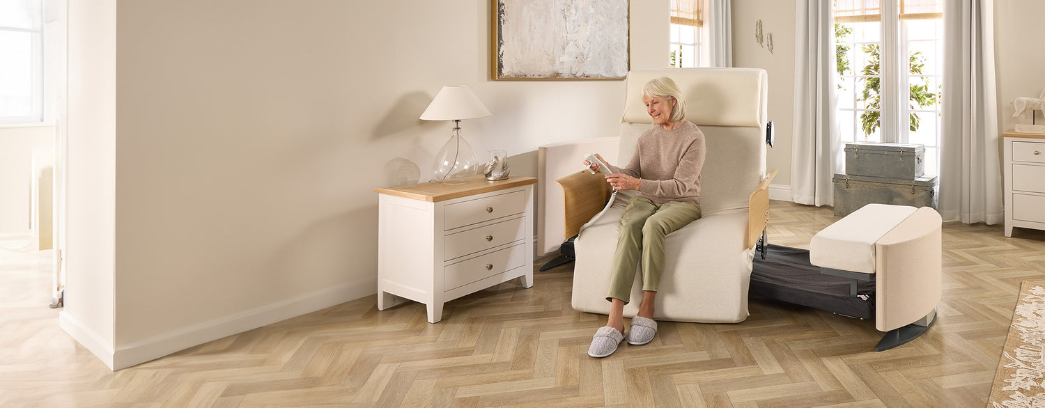 Lady sitting in a Rotating Chair Bed in the chair position, holding the remote control.